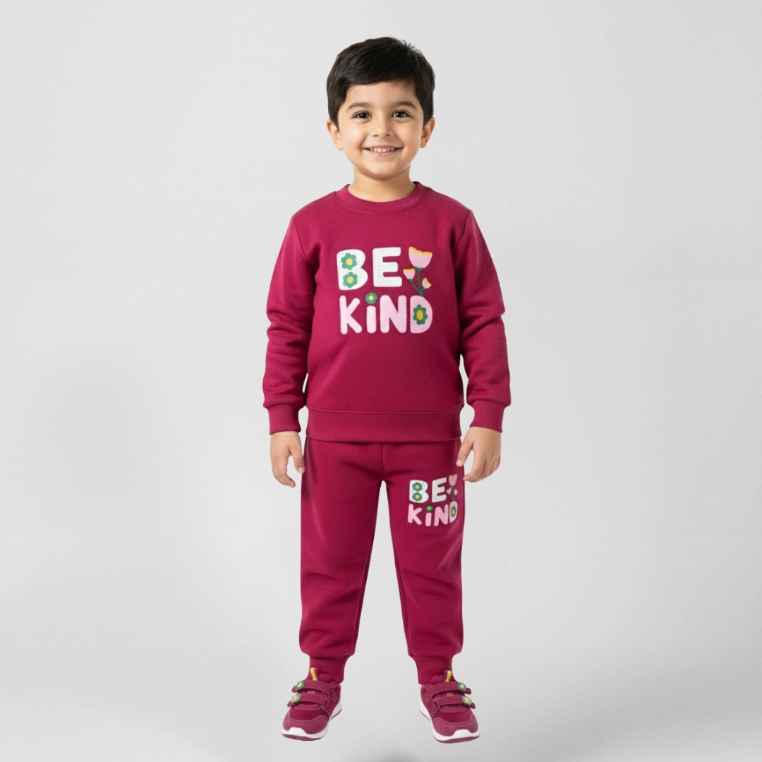 Child wearing a maroon outfit with 'BE KIND' text on a plain background