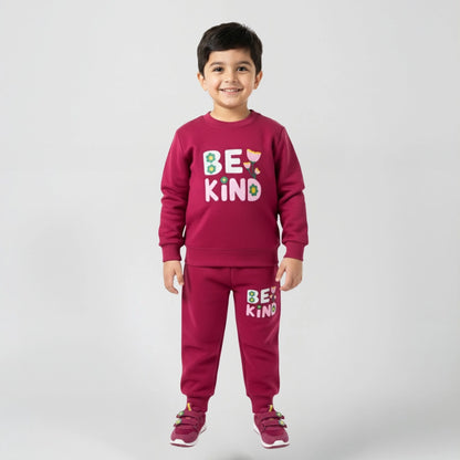 Child wearing a maroon outfit with 'BE KIND' text on a plain background